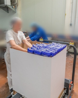 Table élévatrice avec un carton dessus et une femme qui le rempli a coté