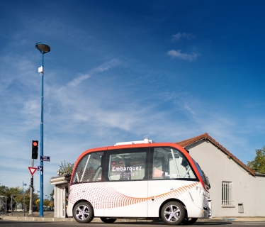 un petit bus blanc et rouge est garé sur le bord de la route.