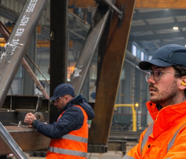 Un collaborateur du bureau d’études en visite dans l’atelier, observant la fabrication d’une passerelle métallique