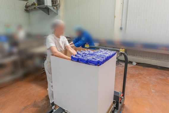 Table élévatrice avec un carton dessus et une femme qui le rempli a coté